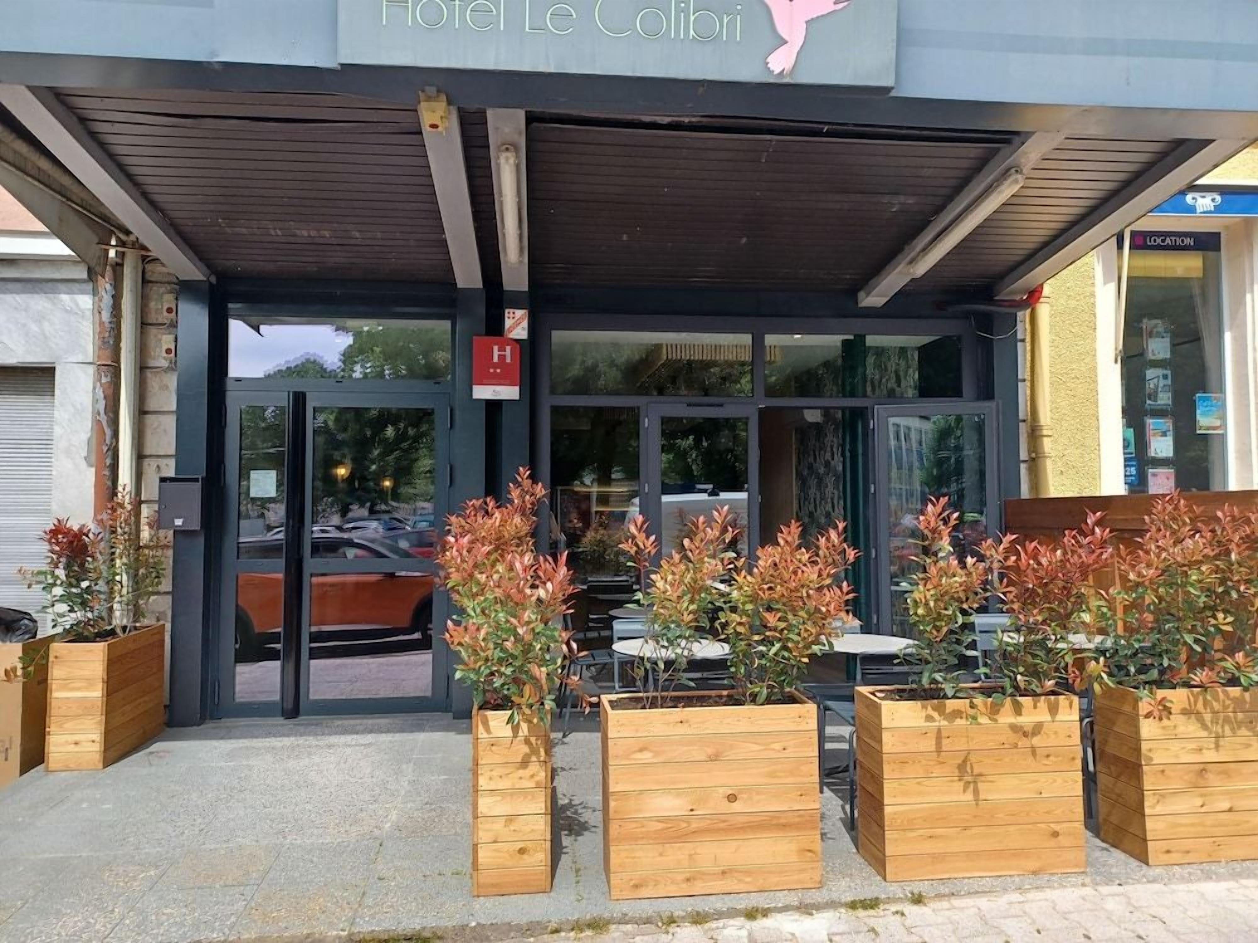L’entrée de l’hôtel Le Colibri, avec un espace extérieur abrité et aménagé avec des plantes en pot.
