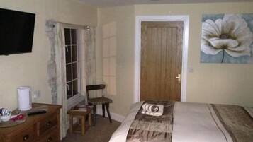 A bedroom with a bed, a dresser, a chair, a door, and a painting on the wall.