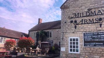A stone building with a sign reading 'MILD MAY ARM'S' and a signboard advertising a restaurant, pub, and hotel.