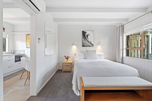 Ein Schlafzimmer mit Bett, Nachttischlampen, einem Nachttisch, einem Gemälde und einem Fenster mit Vorhängen.
