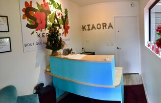 Una recepción con un árbol de Navidad, un certificado enmarcado y una pared con letreros que dicen 'KIAORA' y 'STAY'.