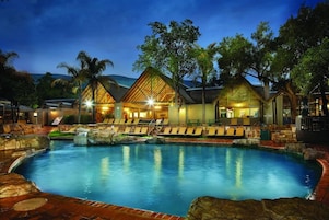 A pool area with lounge chairs and a building with a unique roof structure.