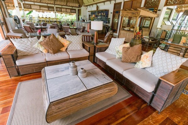 A spacious lounge area with multiple seating options, including sofas and chairs, arranged around a central coffee table.