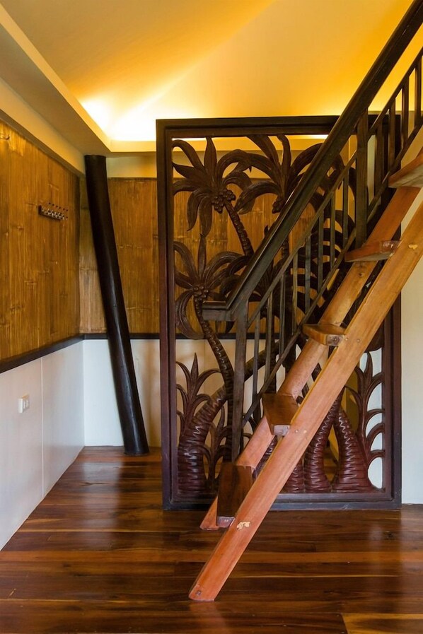A wooden staircase with a decorative railing featuring palm leaf motifs.