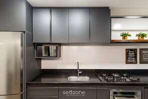 A modern kitchen with grey cabinets, a stainless steel refrigerator, a built-in microwave, a sink with a faucet, a gas stove, and a dishwasher. - Apt. w/ Priv. BBQ & City View Rod0304 (Canela)