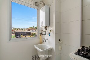 A bathroom with a window, a sink, and a water heater. - Apt. w/ Priv. BBQ & Balcony Pag0207 (Porto Alegre)