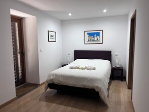 A hotel room with a bed, two bedside tables, a door, and two framed pictures on the wall. - Quinta de São Martinho – Pet-Friendly Country House in Gerês (Soengas)