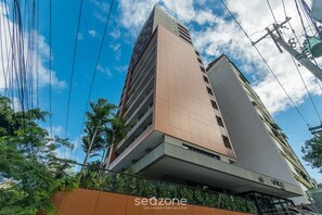 A high-rise building with multiple balconies, a sign indicating '60 UNICO,' and a 'sedzone' branding. - Studio in a Condominium With Pool and gym Eub0301 (Salvador)