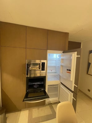 A compact kitchen with a built-in oven, microwave, and a refrigerator with a freezer compartment.