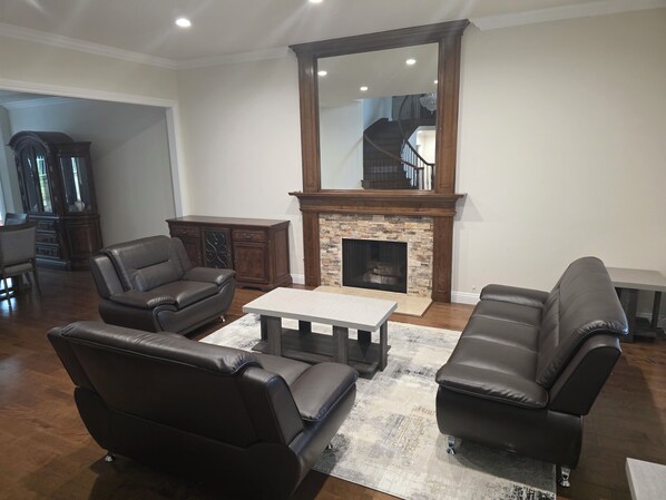 A living room with leather sofas, a fireplace, and a large mirror.