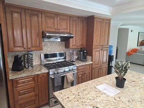 A kitchen with wooden cabinets, a stainless steel stove, a microwave, and a coffee maker. - Spacious 5-bedroom house in marvelous Rowland Heights with AC (Rowland Heights)
