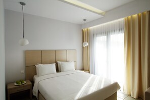 A hotel room with a large bed, bedside tables, and a window with curtains. - Akrogiali Boutique Hotel (Kassandra)