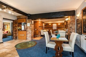 A reception area with a reception desk, a seating area with tables and chairs, and a wall with a menu board.