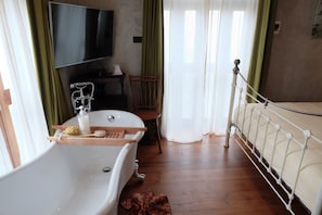 A bedroom with a bathtub, a television, a chair, and a bed. - Roomquest Rimrabeang At Amphawa (Amphawa)