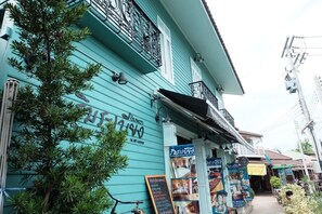 A turquoise building with a balcony and signage for a cafe. - Roomquest Rimrabeang At Amphawa (Amphawa)