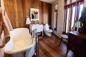 A bathroom with a freestanding bathtub, a white sink, a toilet, and a wooden floor. - Roomquest Rimrabeang At Amphawa (Amphawa)