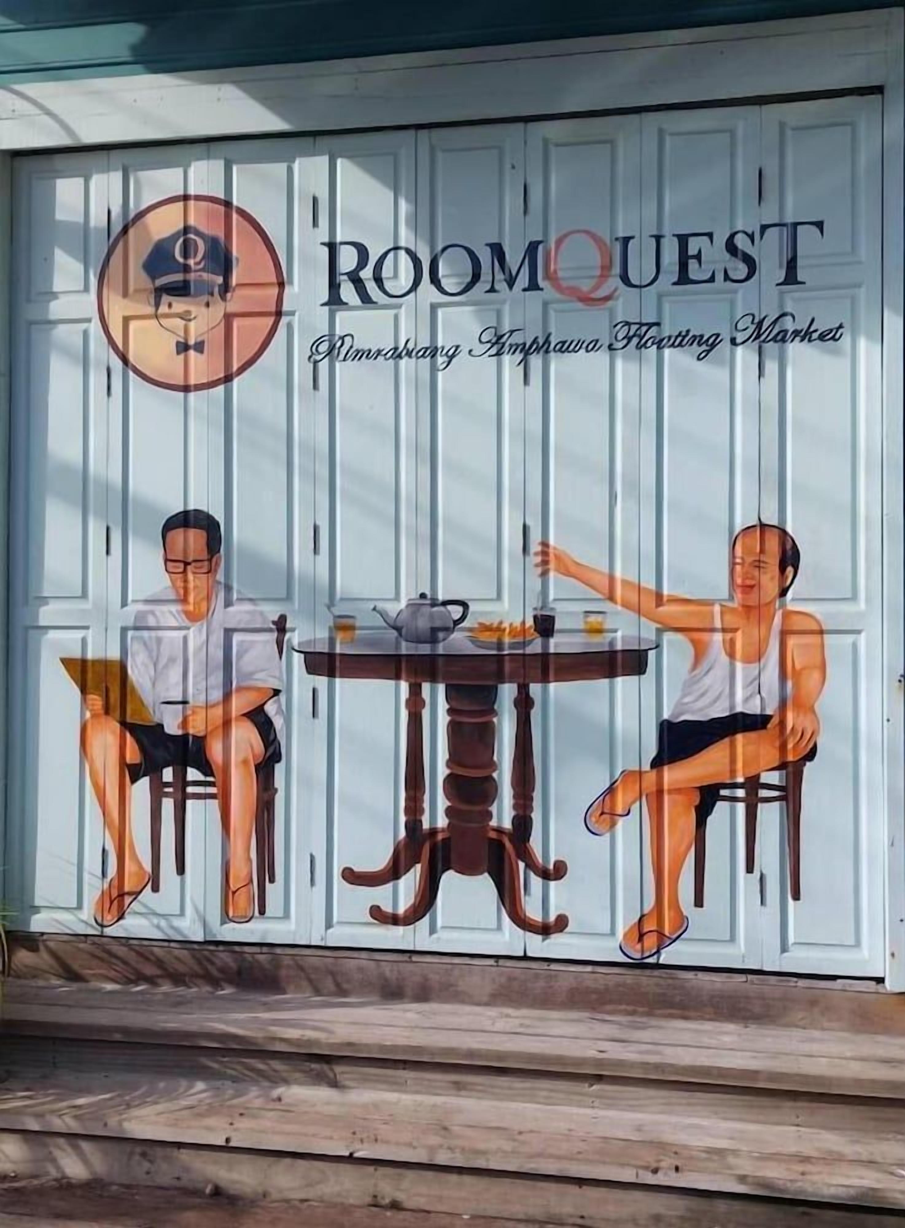 Un mur orné d’un logo « ROOMQUEST » et d’une représentation de deux personnes dînant à une table.