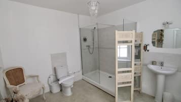 A bathroom with a glass-enclosed shower, a white sink, a chair, and a wooden ladder.