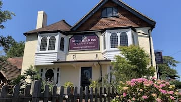 A two-story building with a sign for 'Kings Head Inn' indicating it is a place for eating, drinking, and staying.