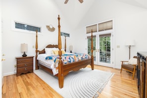 A bedroom with a wooden four-poster bed, a nightstand, a lamp, and a view of the outdoors through a glass door. - Lakefront, Hot Tub, Dock, Kayaks, SUPs, Games, Fire pit (Boydton)