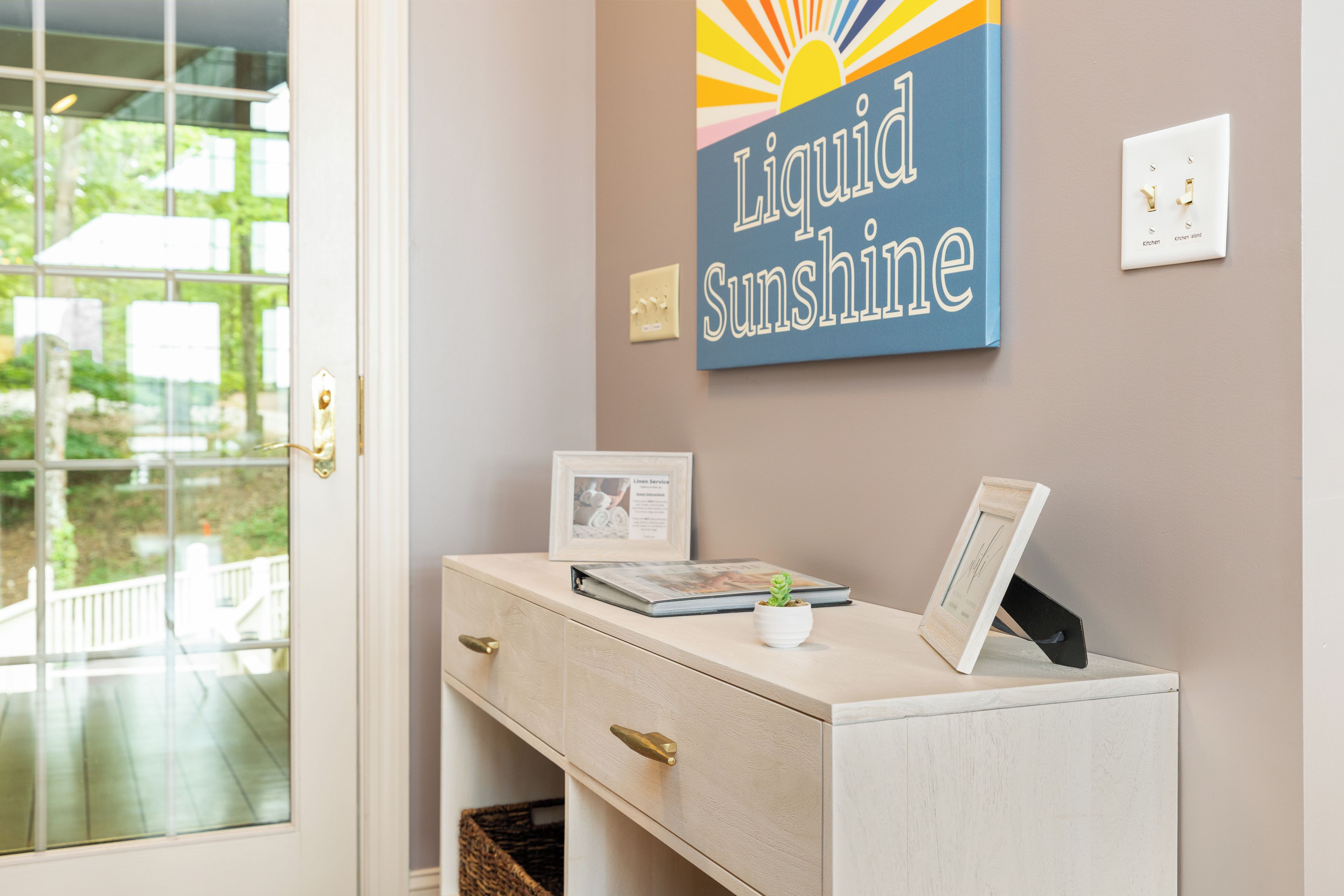 A reception desk with a framed picture, a small potted plant, and a sign reading 'Liquid Sunshine'.