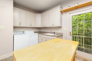 A kitchen with white cabinets, a built-in oven, a sink, and a window with a view of greenery. - Lakefront, Hot Tub, Dock, Kayaks, SUPs, Games, Fire pit (Boydton)