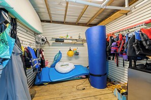 A room with a blue exercise mat, a punching bag, and various bags and equipment on racks. - Lakefront, Hot Tub, Dock, Kayaks, SUPs, Games, Fire pit (Boydton)