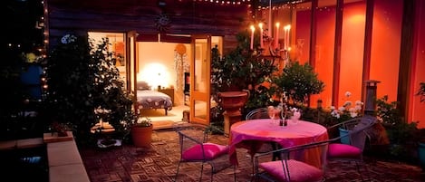 A patio area with a round table and chairs, a small indoor space with a bed, and a view of the sky.