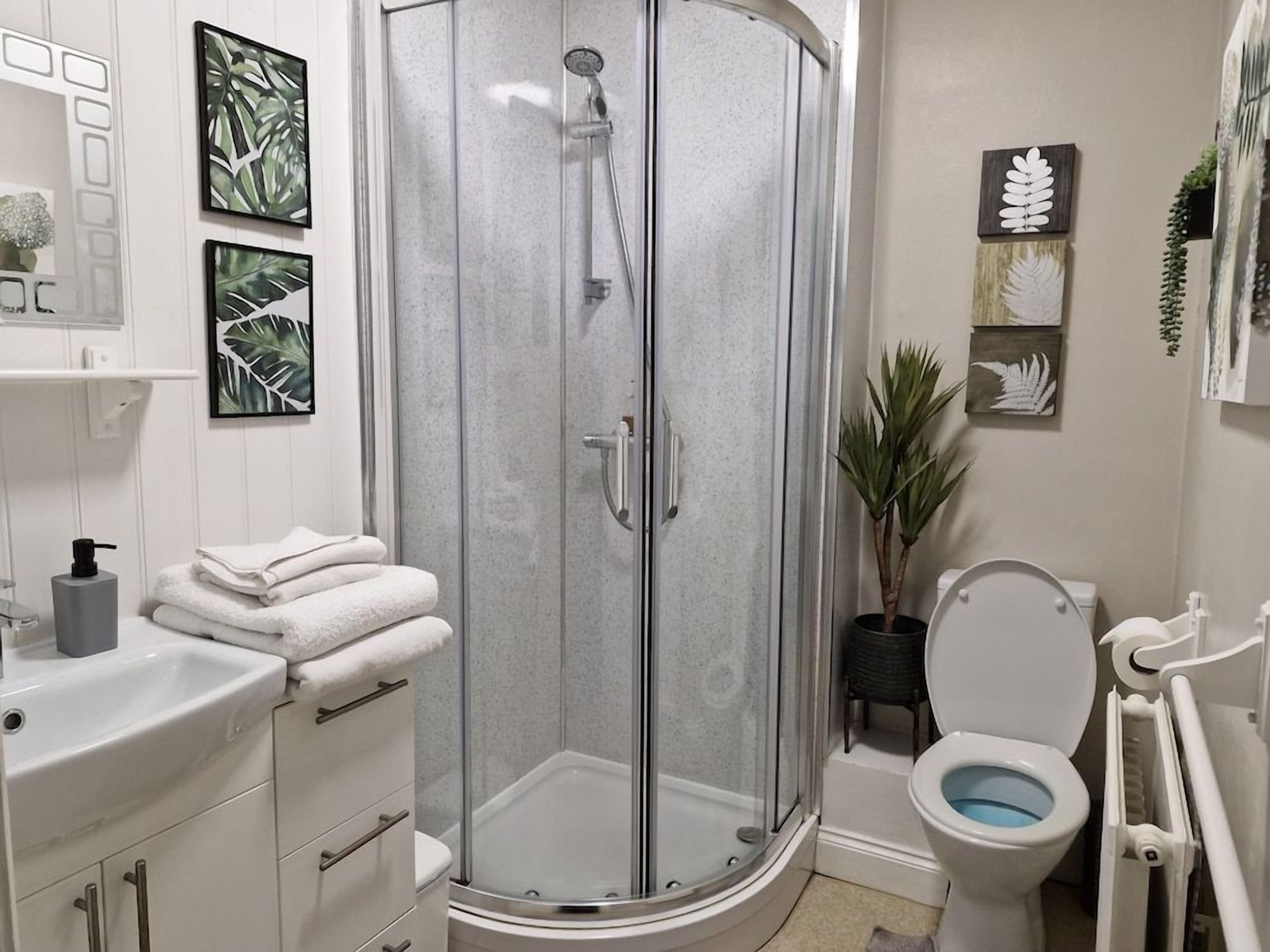 Een badkamer met een glazen douchecabine, een wit wastafelmeubel en toilet.