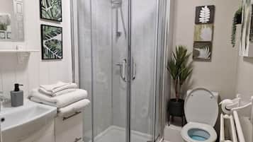 Een badkamer met een glazen douchecabine, een wit wastafelmeubel en toilet.