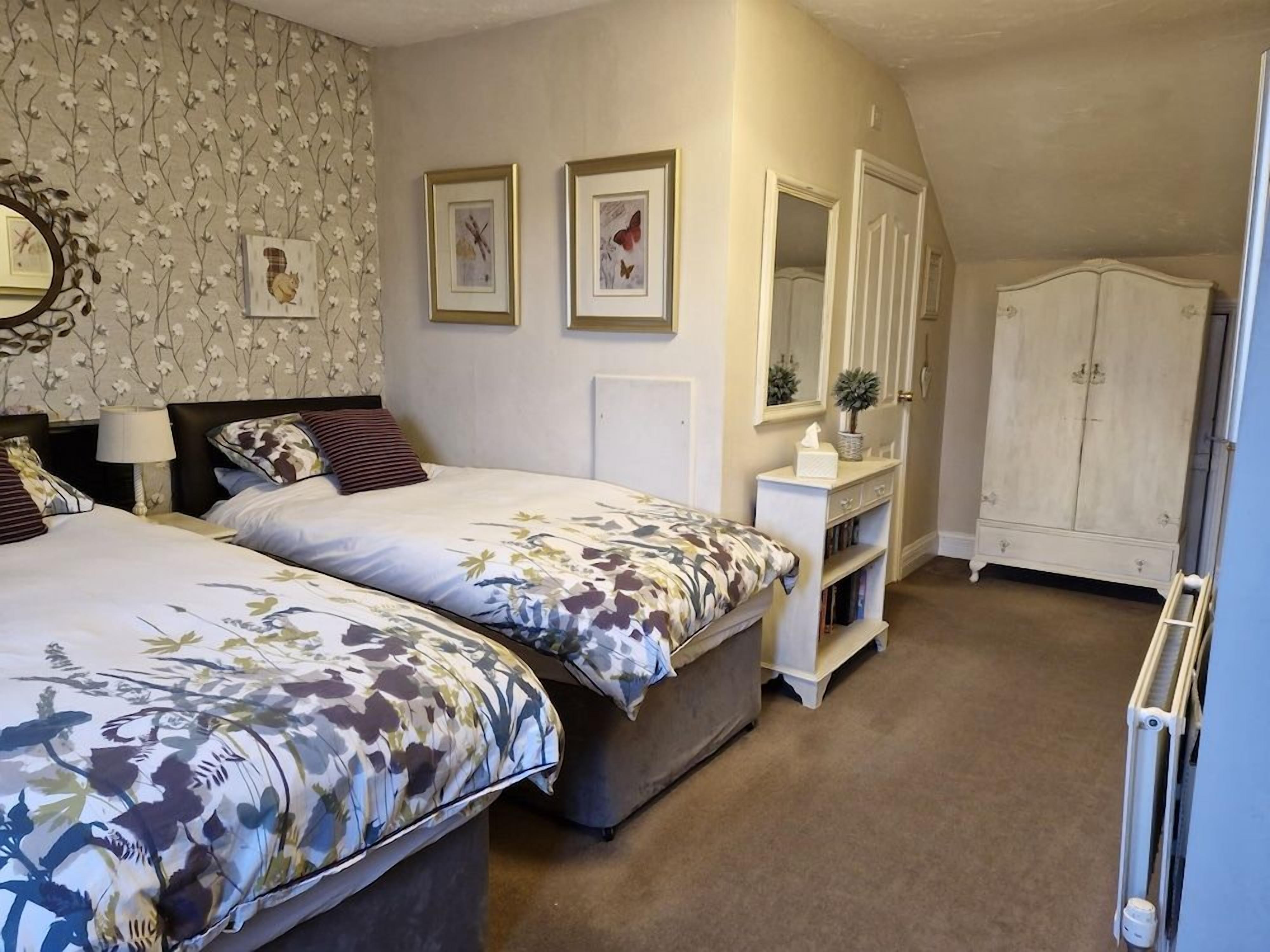 Een slaapkamer met twee bedden, een dressoir, een spiegel en een radiator.
