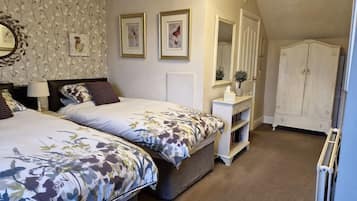 Een slaapkamer met twee bedden, een dressoir, een spiegel en een radiator.