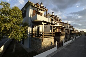 A row of modern houses with balconies, stone foundations, and a clear sky.