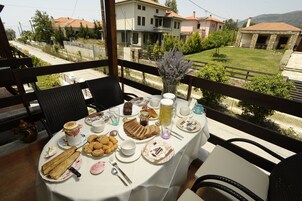 A table set for breakfast with various food items and drinks, overlooking a residential area with houses and greenery.