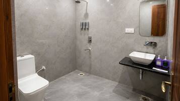 A modern bathroom with a toilet, shower, and sink.