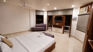 A modern bedroom with a large bed, a seating area, and a balcony with a view. - ZenithSuites - Vrindavan (Vrindavan)
