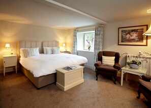 A hotel bedroom with a large bed, bedside tables, a chair, a window with curtains, and a framed picture on the wall. - Barnsdale Lodge Hotel And Restaurant (Oakham)