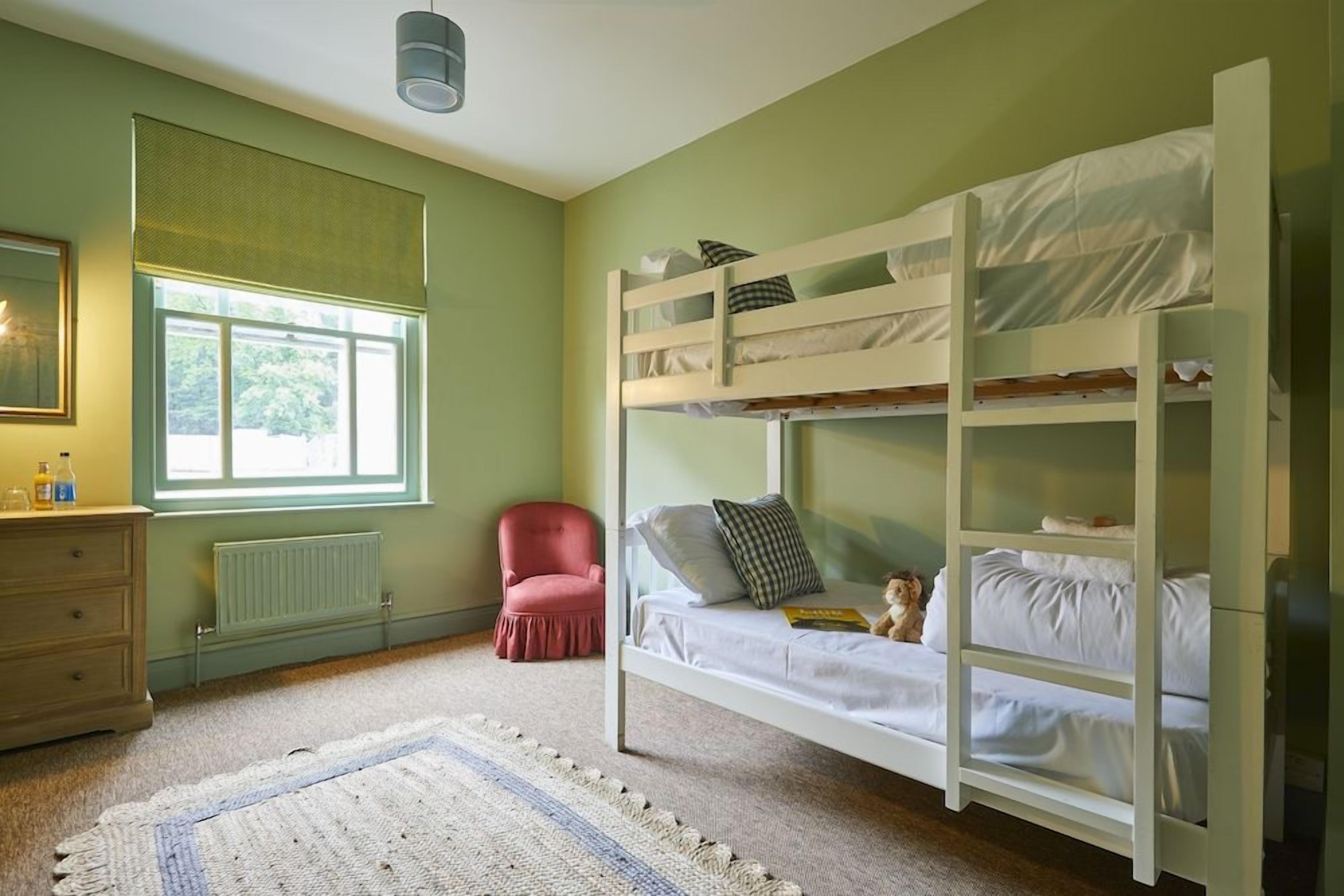 Ein Schlafraum mit Etagenbett, Fenster, Heizkörper, Stuhl und Nachttisch.