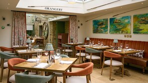 A restaurant interior with wooden tables, cushioned chairs, and a central seating area.