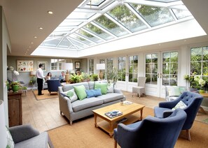 A spacious living area with a high ceiling and skylight, furnished with a sofa, chairs, and a coffee table.
