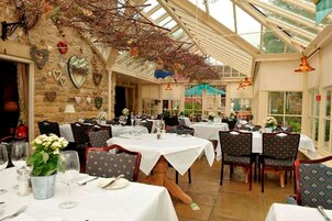 Un restaurante con varias mesas, sillas y techo de cristal.