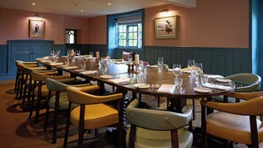 Une salle à manger avec une longue table dressée pour le repas, entourée de chaises.