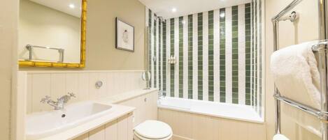 A bathroom with a white sink, a toilet, a bathtub, and a shower with green tiles.
