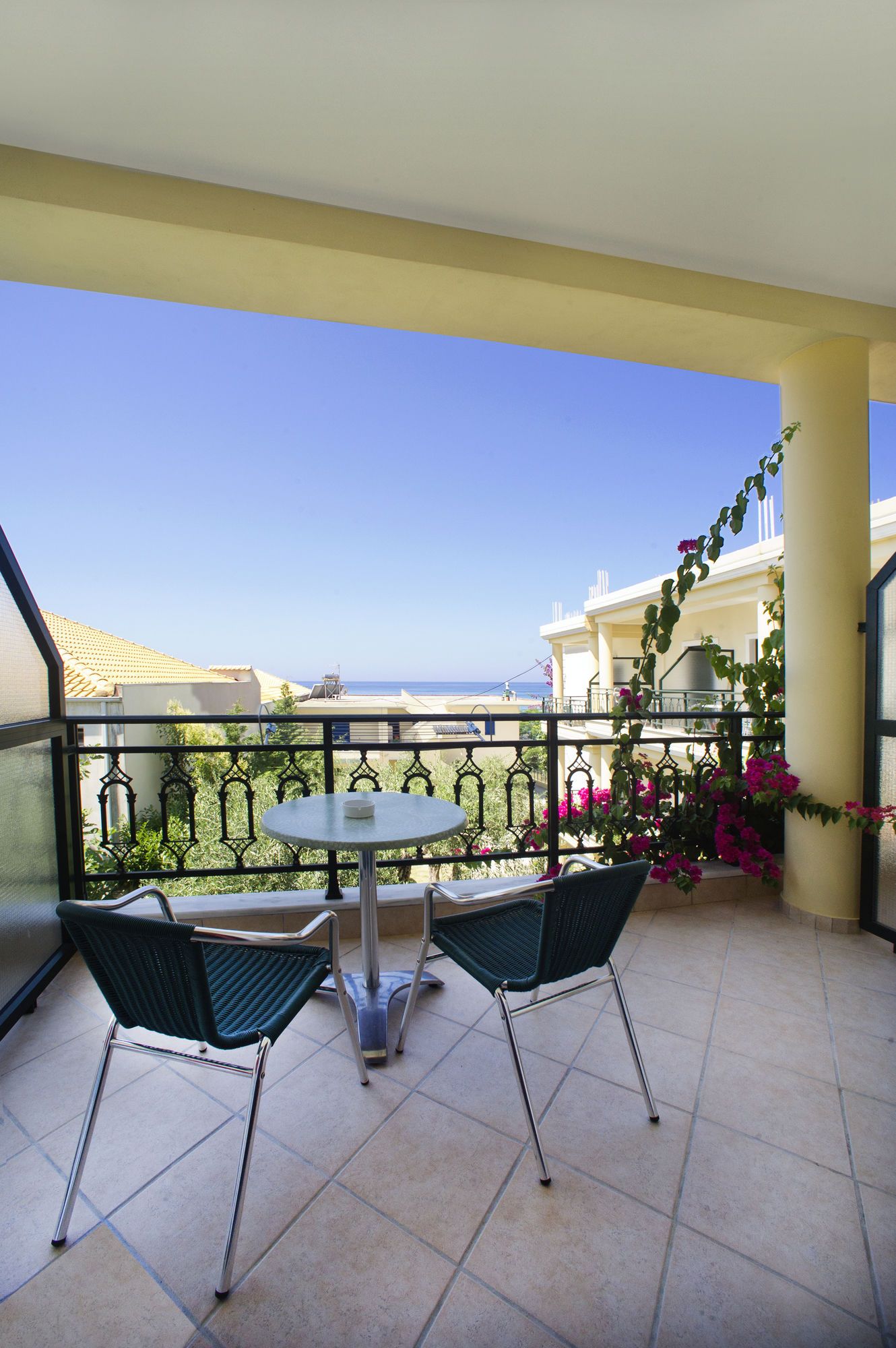 Ein Balkon mit zwei Stühlen und einem Tisch, mit Blick auf die Küste.