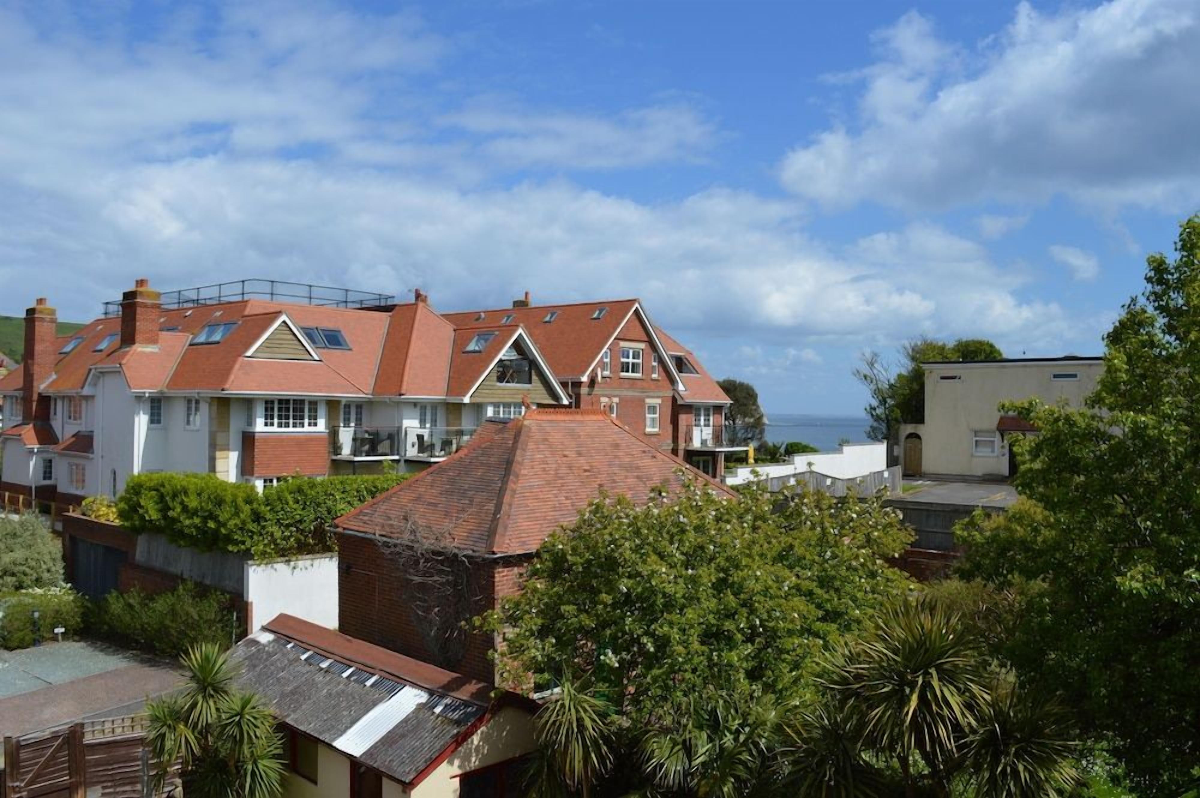 A residential building with a sloped roof, multiple windows, and a view of the sea.