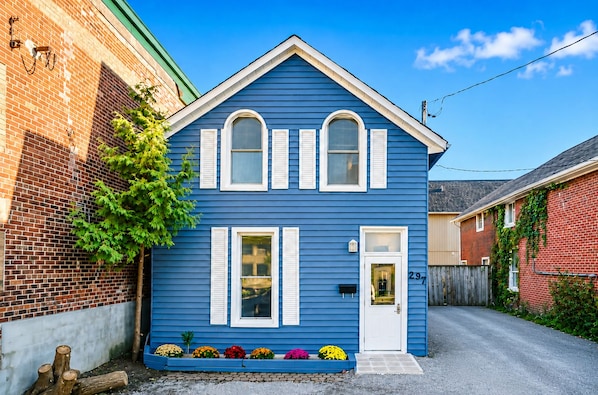 Una casa azul de dos pisos con contraventanas blancas, una puerta principal y un buzón.