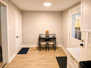Un comedor con una mesa preparada para dos, un florero con flores y una ventana con vistas.