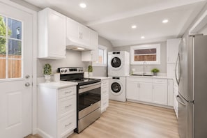 Una cocina moderna con armarios blancos, electrodomésticos de acero inoxidable y piso de madera.