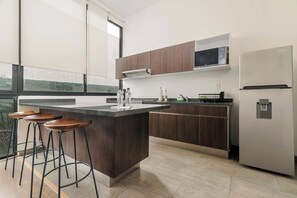 A modern kitchen with a central island, bar stools, a microwave, and a refrigerator. - w* | Deluxe 1BR in Escandón w/ Private Terrace (Ciudad de México)