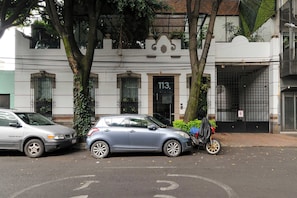 A street view with two parked cars, a building with the number 113, and a tree with vines. - w* | Deluxe 1BR in Escandón w/ Private Terrace (Ciudad de México)